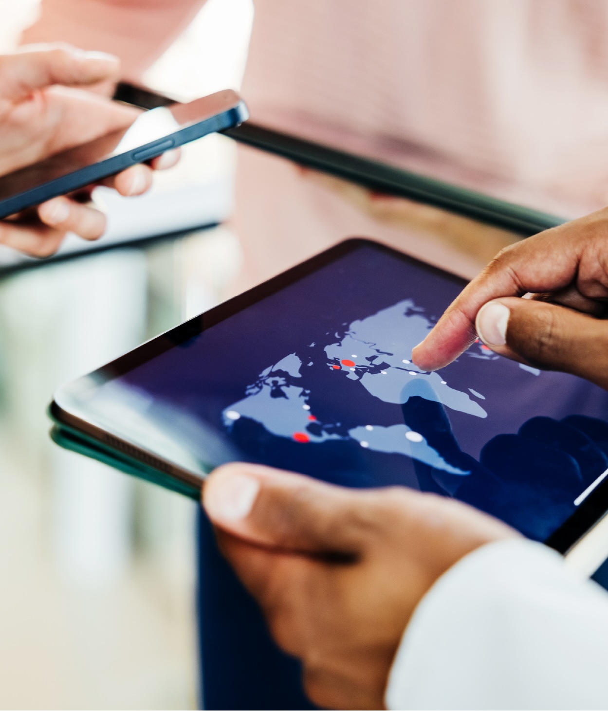 Employees look at global hotspots on an atlas displayed on mobile screens.