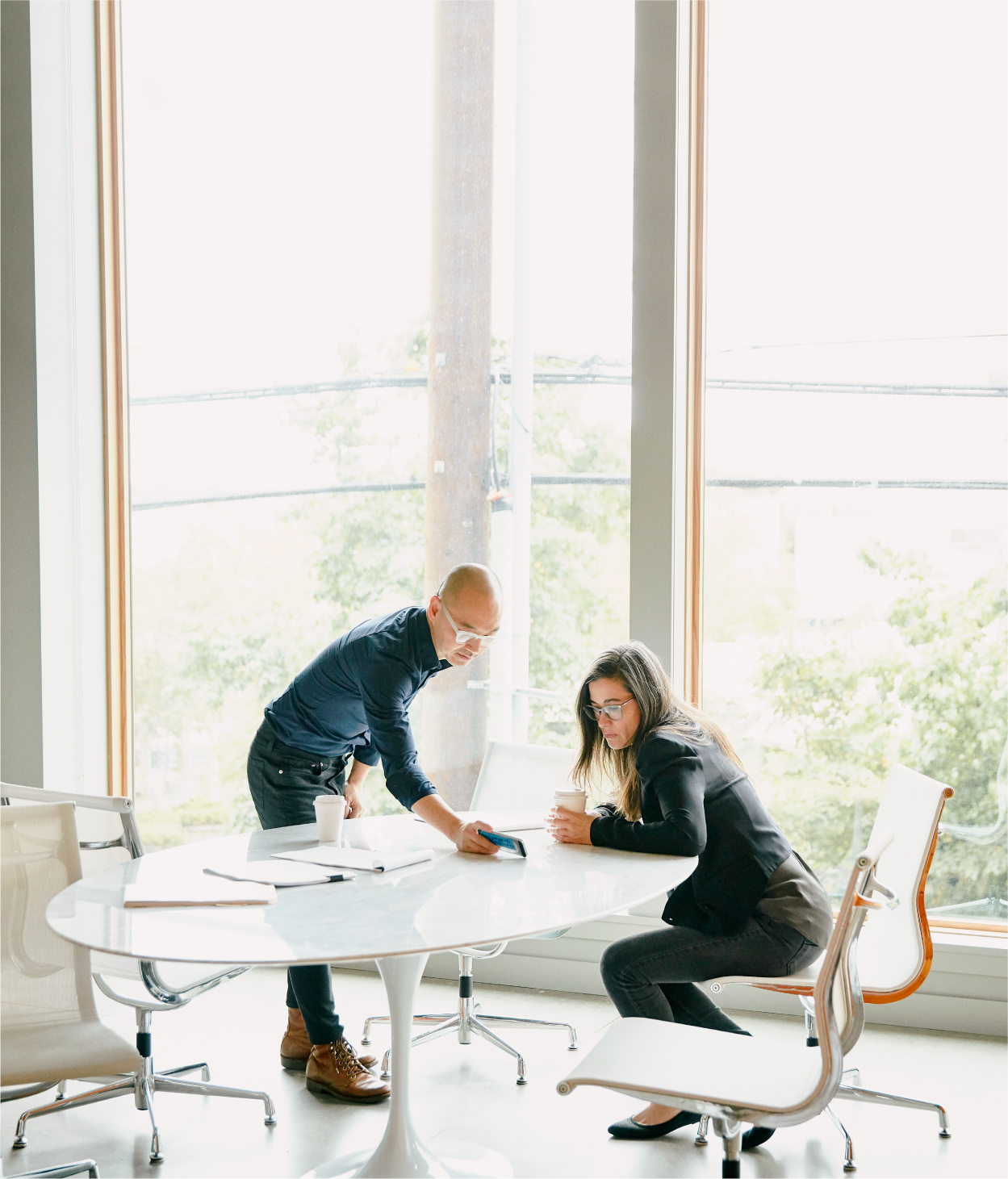 Man and woman coworkers looking at cell phone in conference